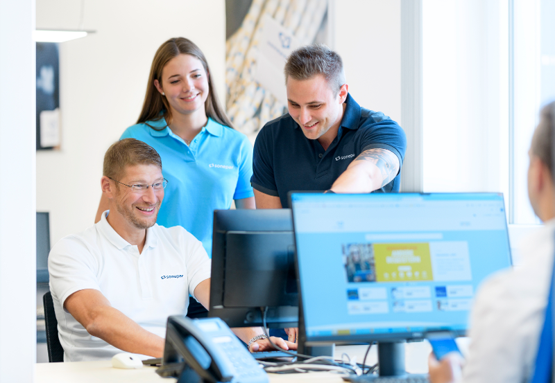 Sonepar employees collaborating around office computers